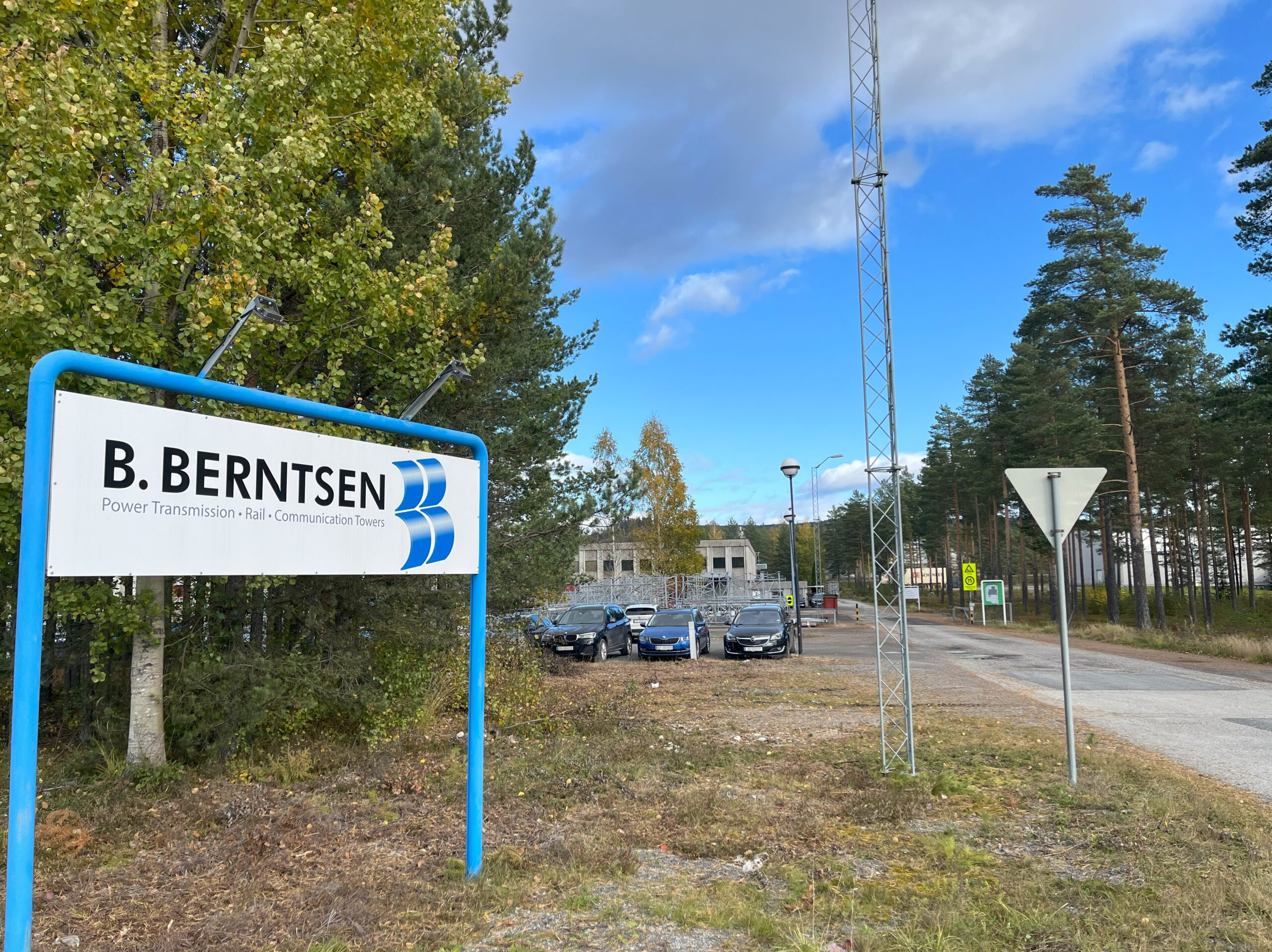 Skilt med Brødrene Berntsen logo. Fabrikken i bakgrunn.